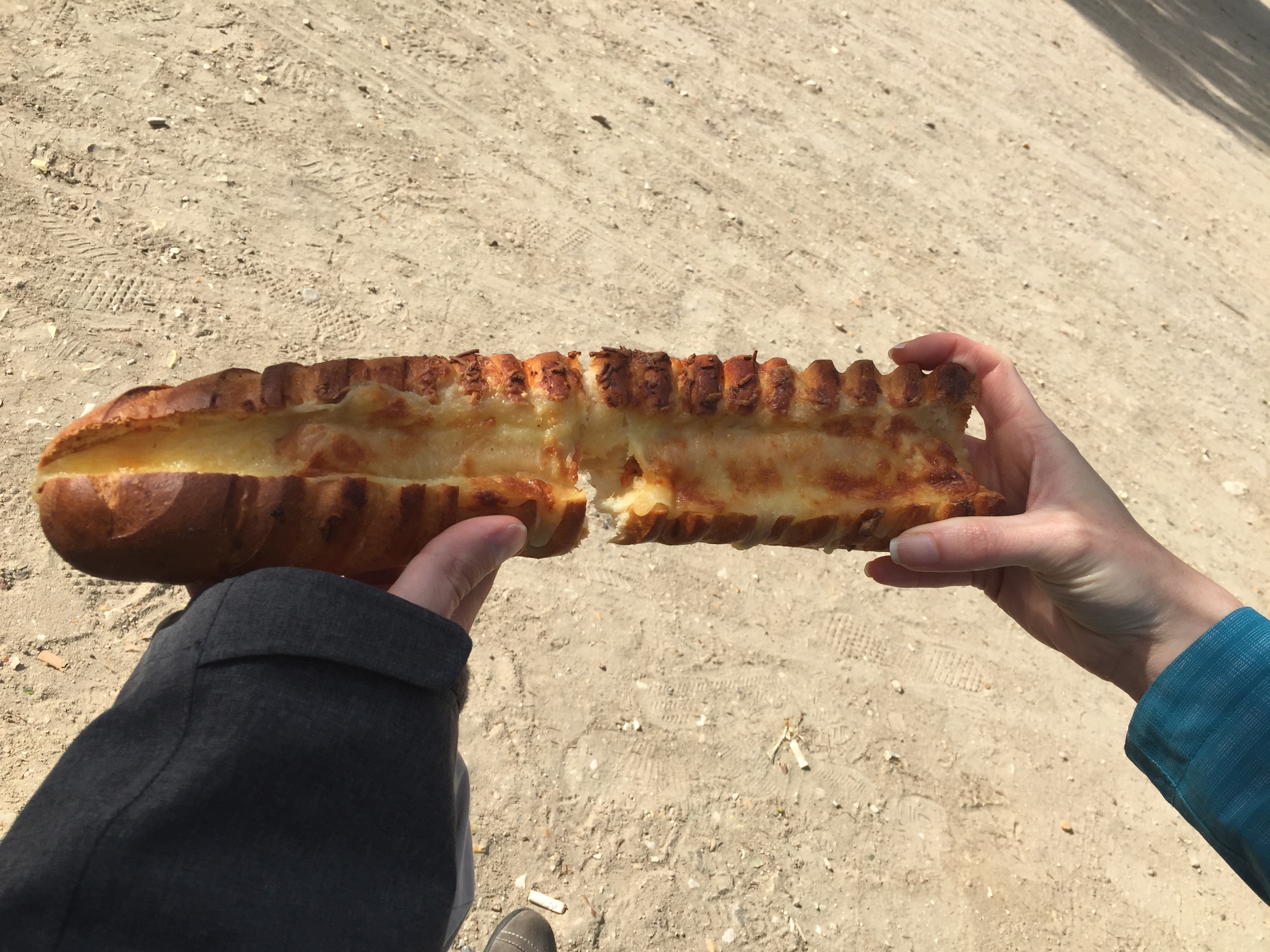 Extra long parisian hot dog in baguette with cheese on top.