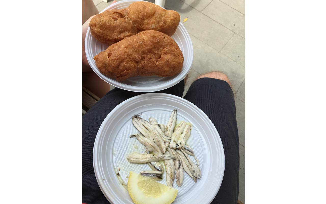Two white plates. One with fried bread and the other with anchovies and lemon.