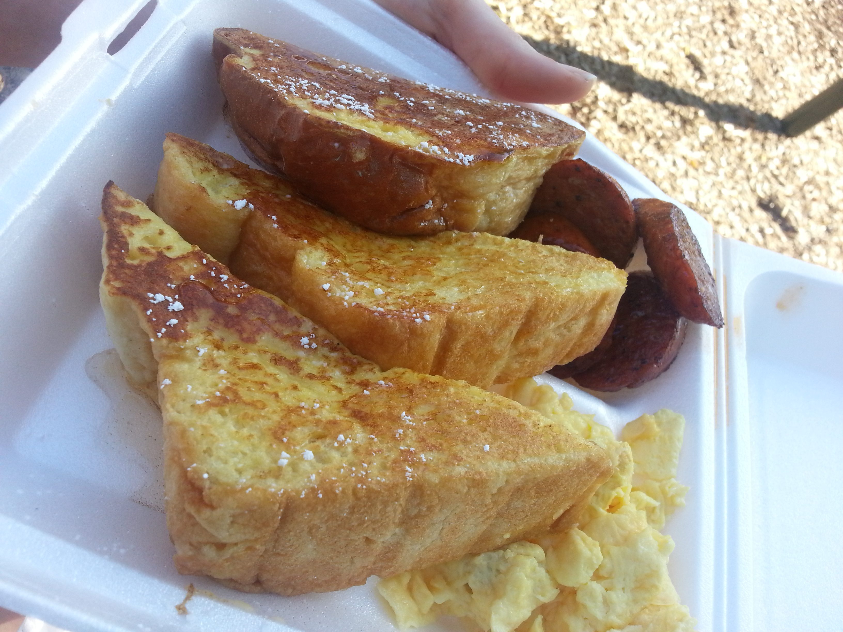 French toast, eggs, and sausage in a styrofoam container.