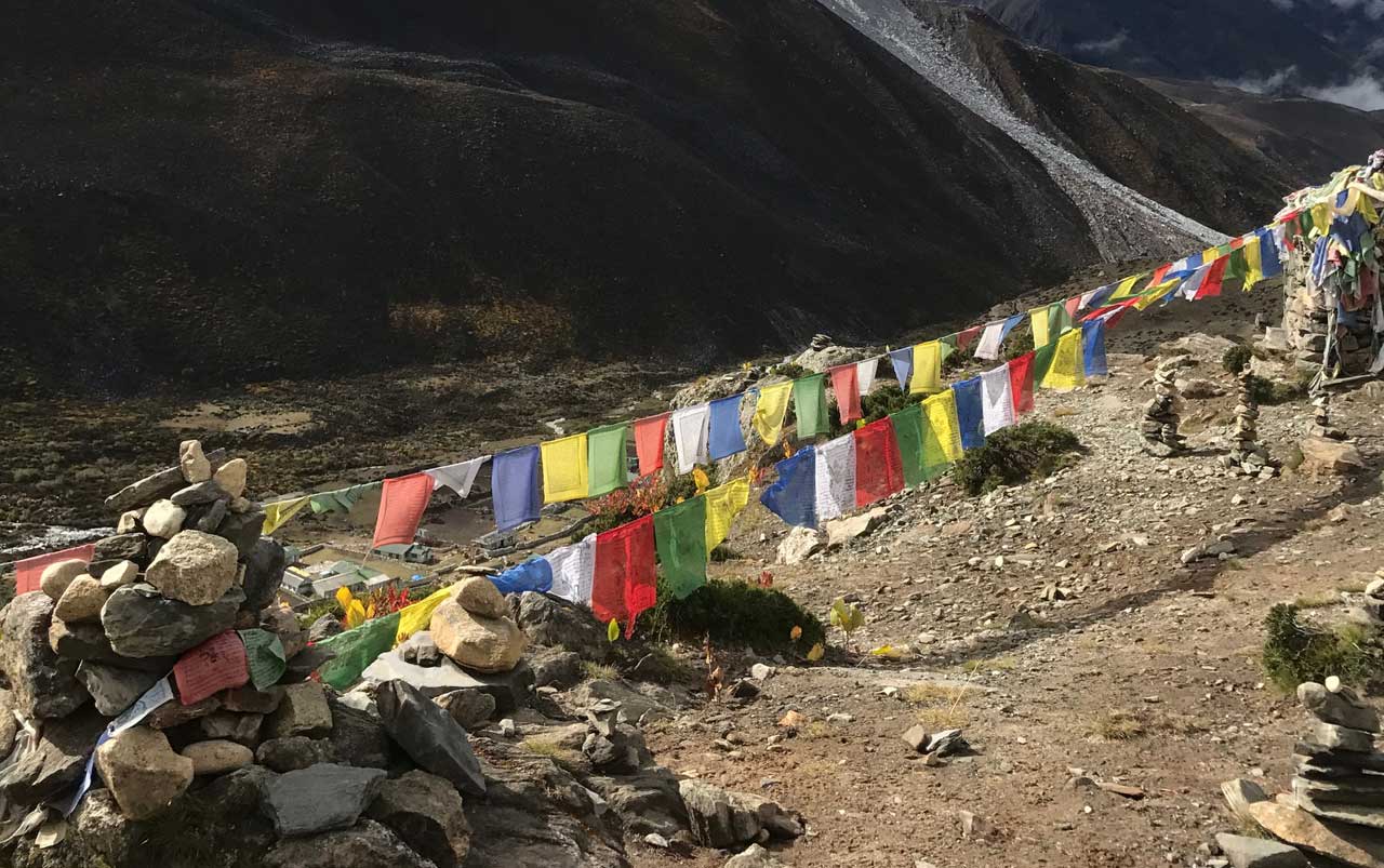 Prayer flags spread across an area surrounded by stacked rock cairns.