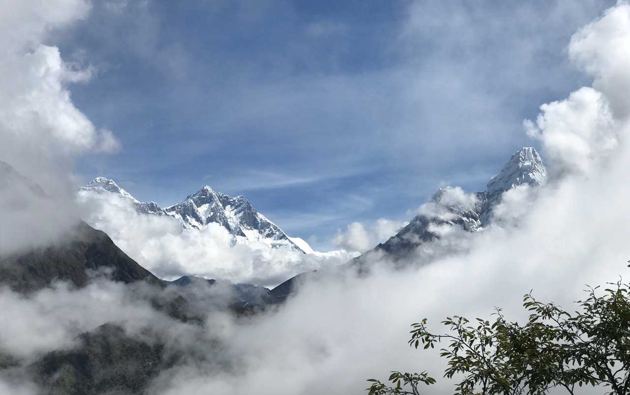 Mountain peaks surrounded by white clouds against a blue sky.